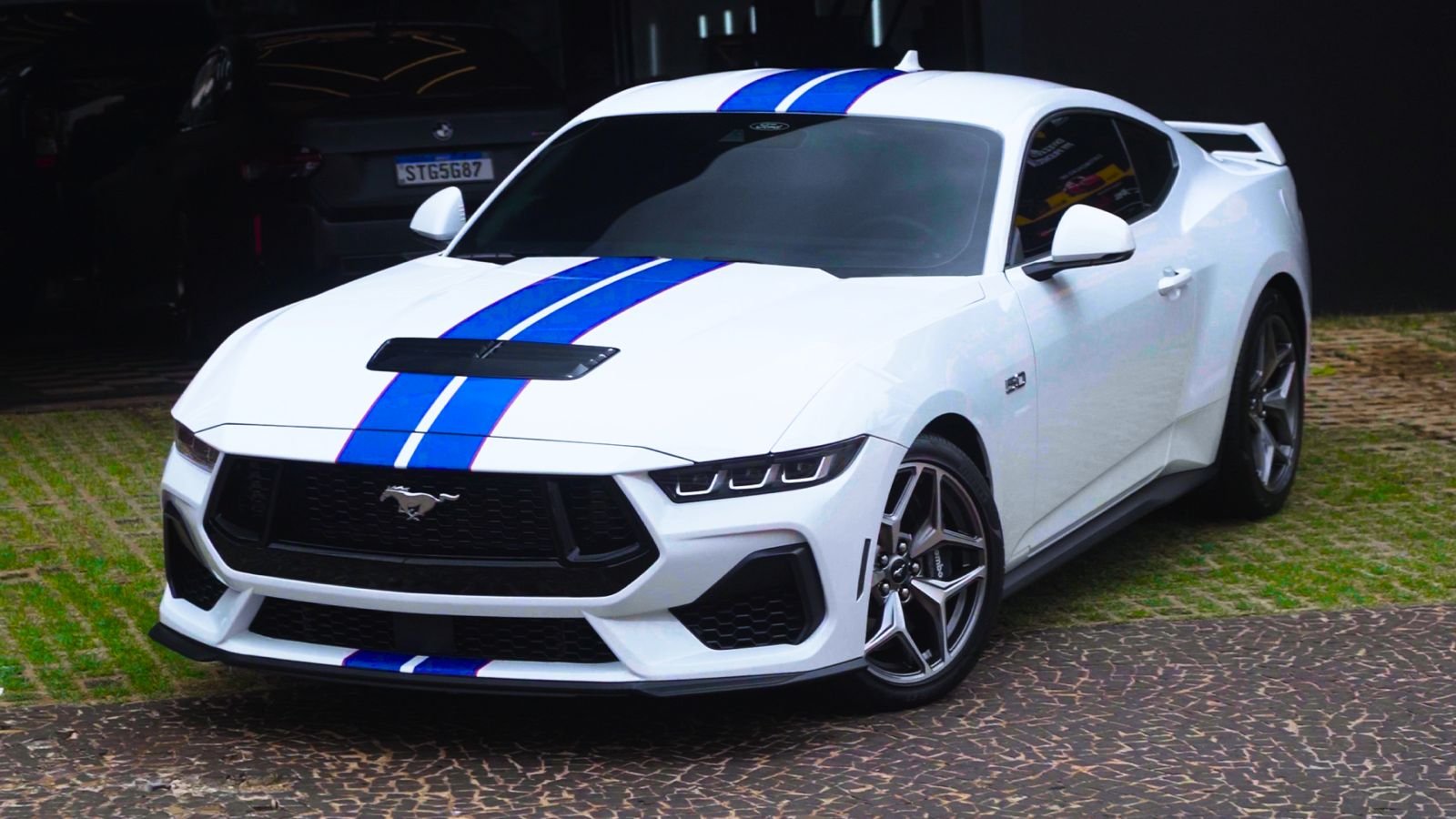 Mustang branco com faixas azuis em área externa
